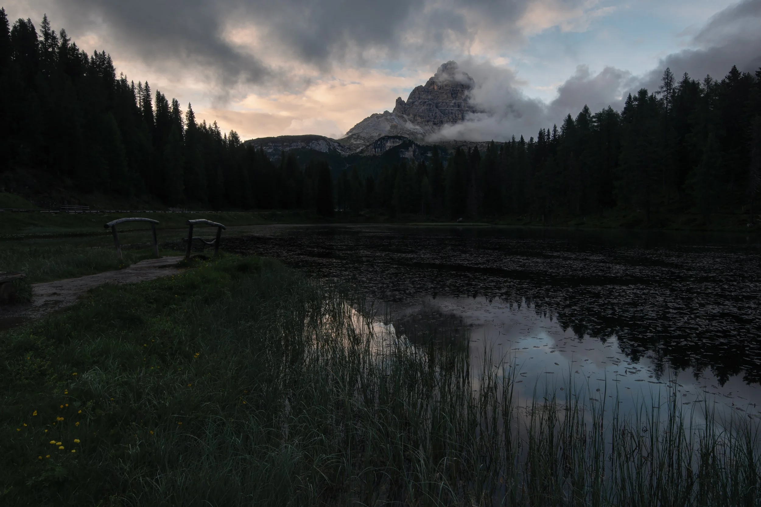 Fine art  minimalist picture of Lago antorno Italian Dolonites at dusk with drifting clouds around the peak of Tre cime de laverado reflecting in the water of the lake.