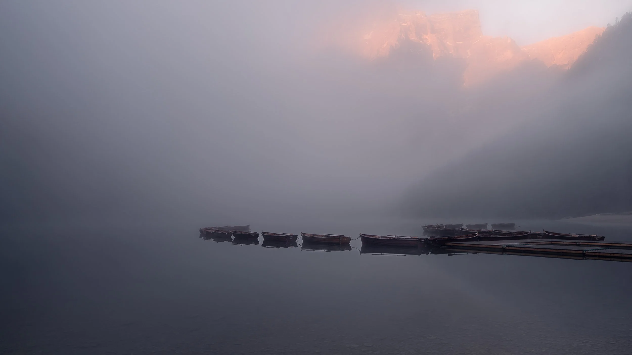 Misty morning at Lago di braies with a boats on the lake