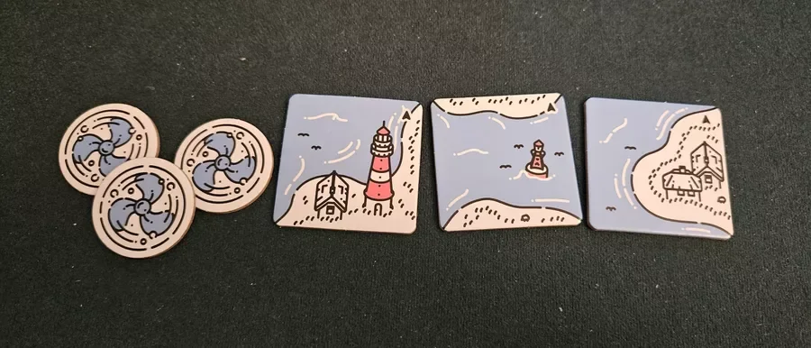 Game tokens for Beacon Patrol and three square tiles with lighthouse and house illustrations on a black surface.