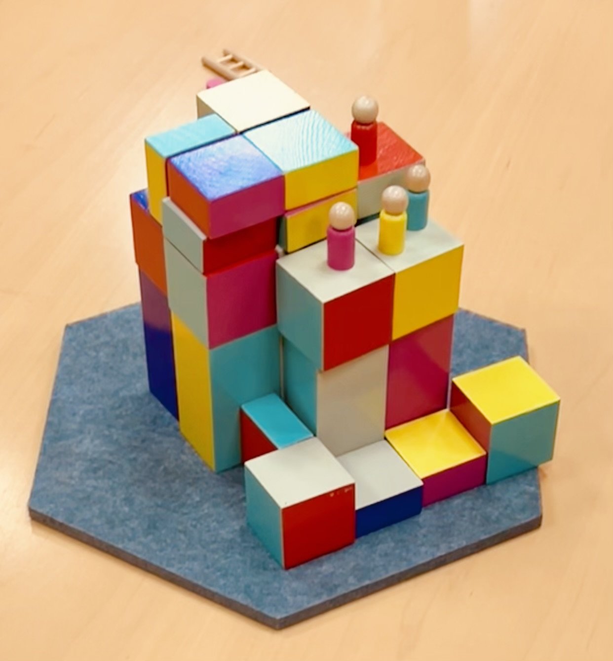 Colorful wooden blocks arranged in a structure on a gray felt board.