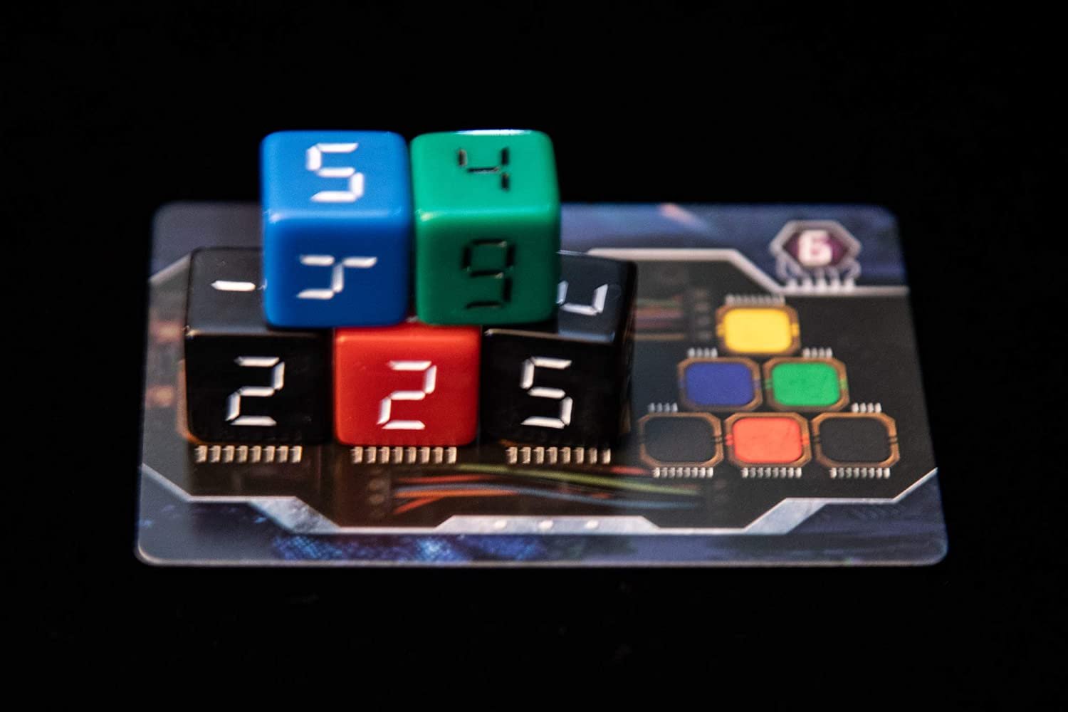A stack of five colorful numbered cubes on top of a game card. The cubes are blue with the number 5, green with the number 4, blue with the number 3, red with the number 2, and black with the number 5.