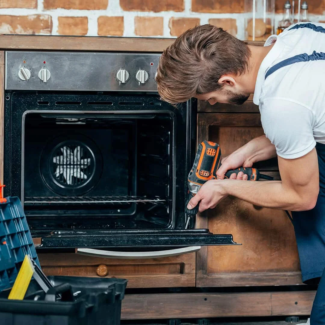 young-repairman-in-protective-workwear-fixing-oven-89JVRJL-1.jpg