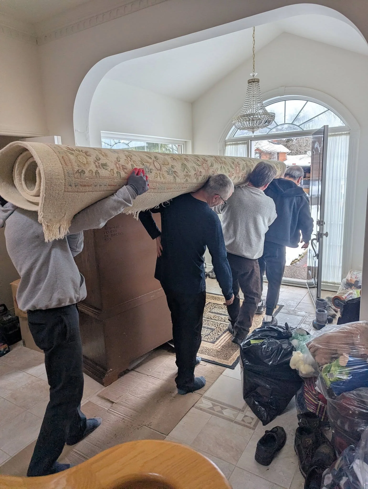 Volunteers movers carry out a long carpet to a moving van.