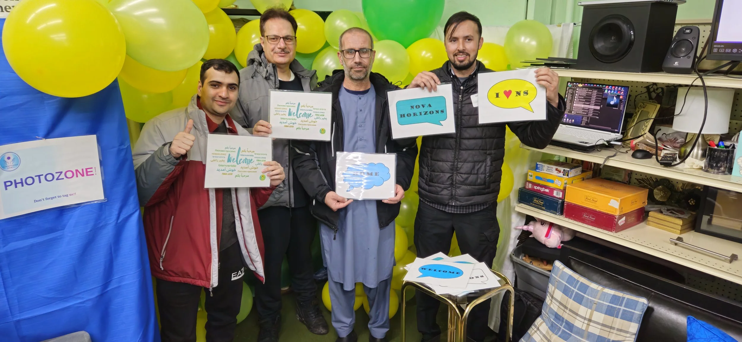 Four volunteers hold Welcome Signs at Nova Horizons photo booth.