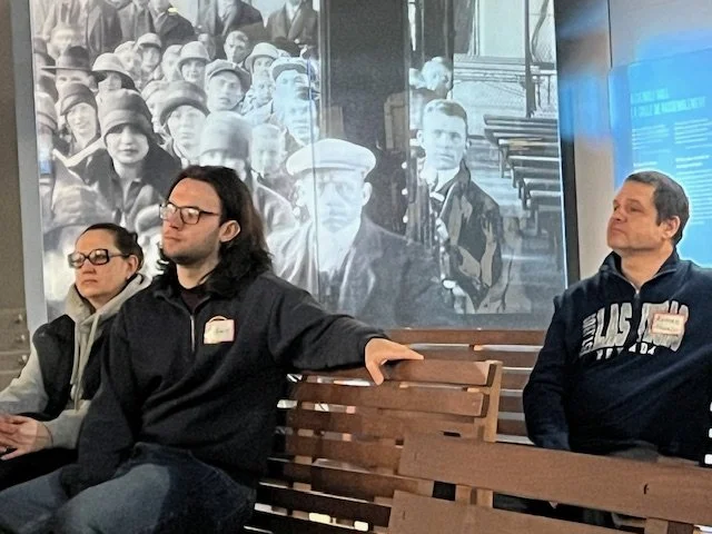 People listen to a speaker at Pier 21 Museum.