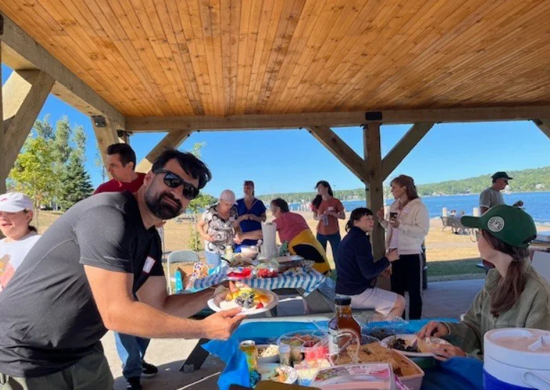 A smiling man fills his plate at an outdoor picnic event with Nova Horizons.