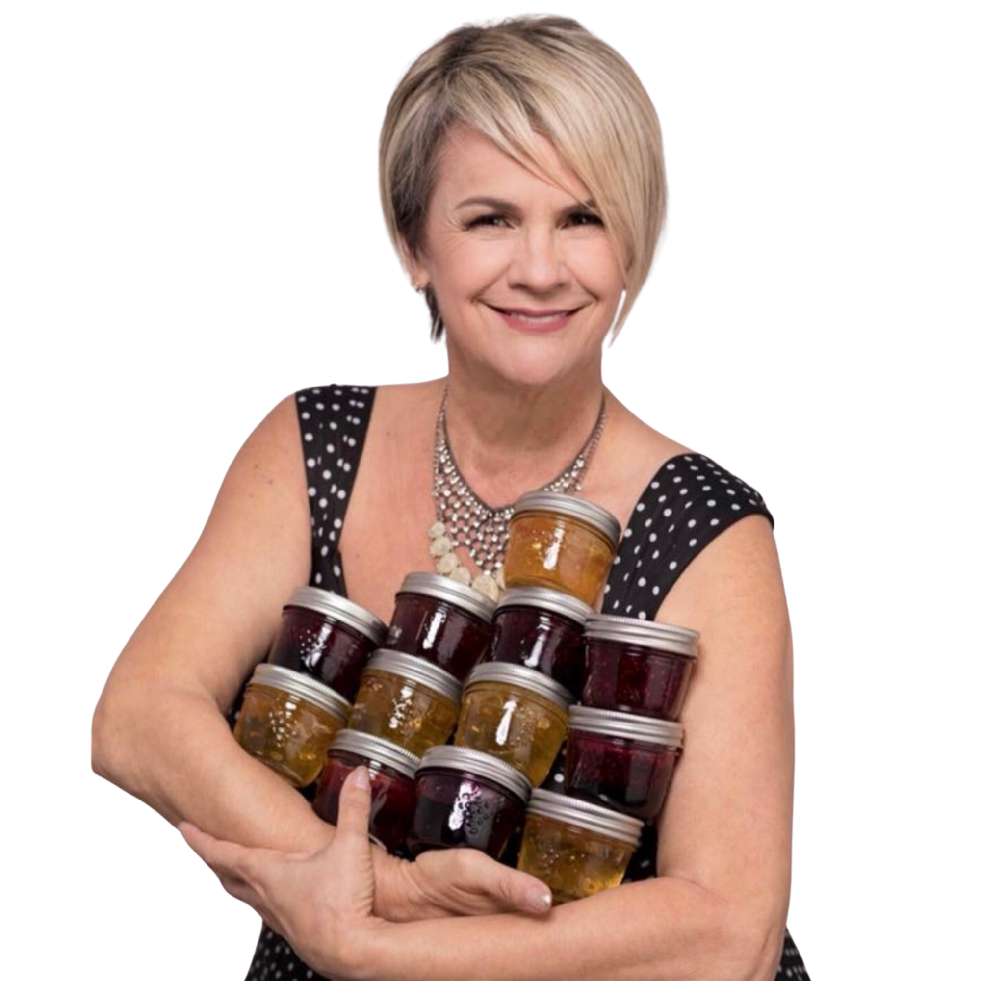A smiling woman with short blonde hair, wearing a black polka-dot dress and a pearl necklace, holding several jars of jam or jelly.
