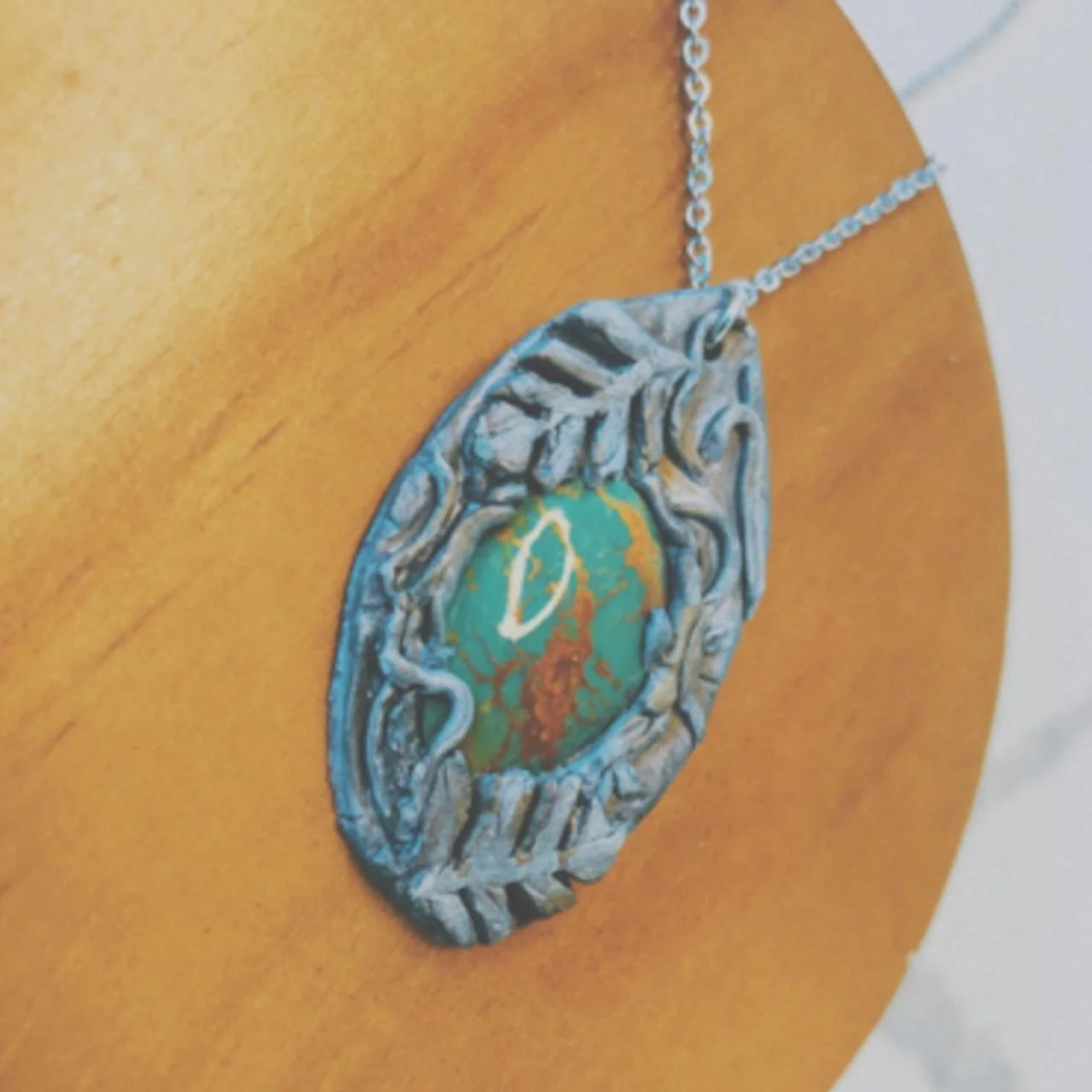 Close-up of a decorative silver necklace with a large, colorful pendant on a person's neck.