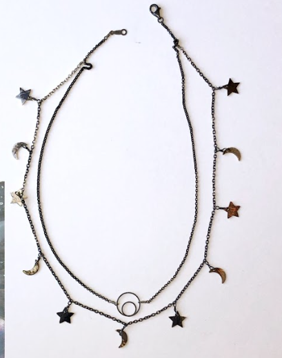 Two layered silver necklaces with star and moon charms on a white background.