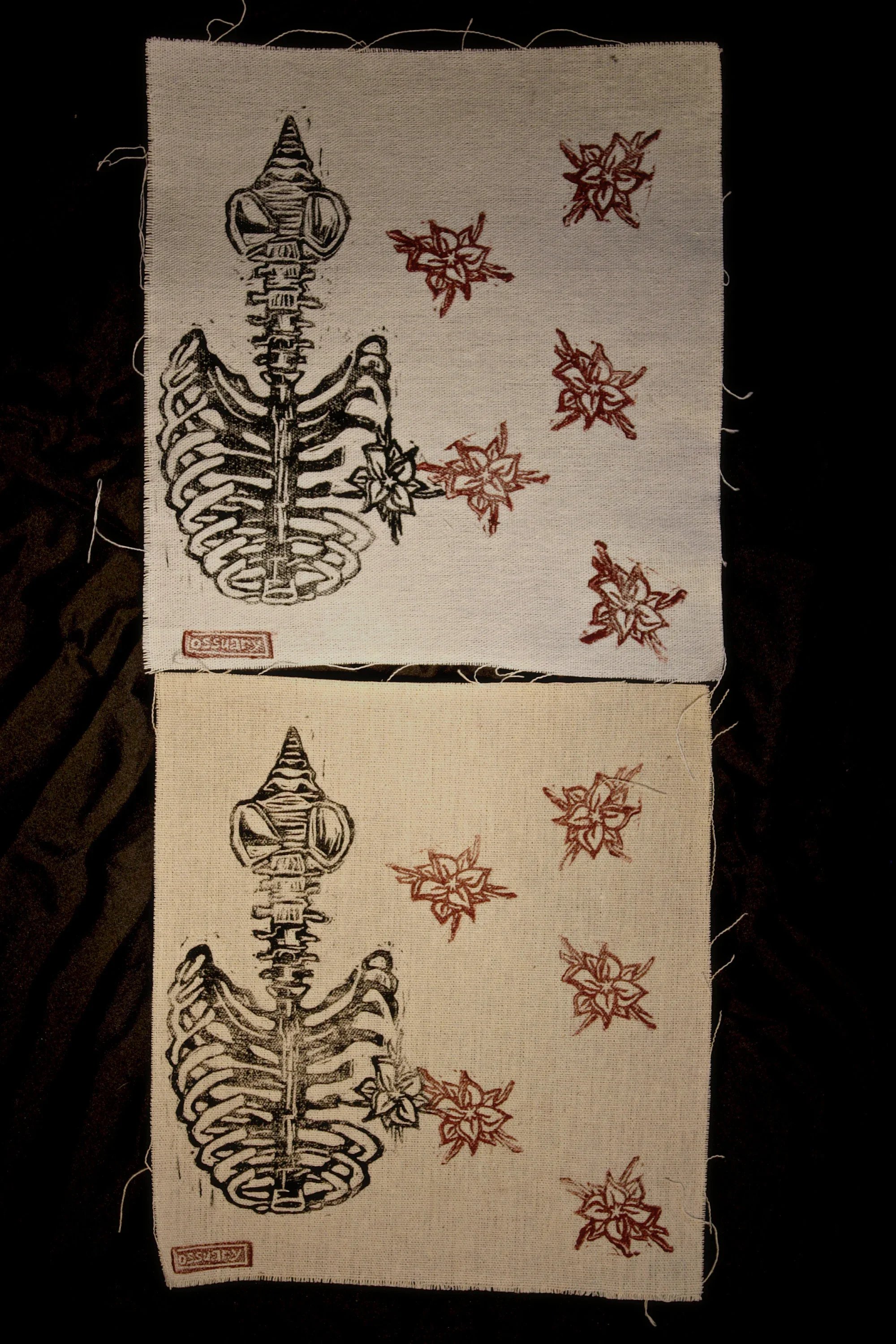 Two cloth napkins with black and red designs of a human skeleton and red flowers placed on a dark surface.