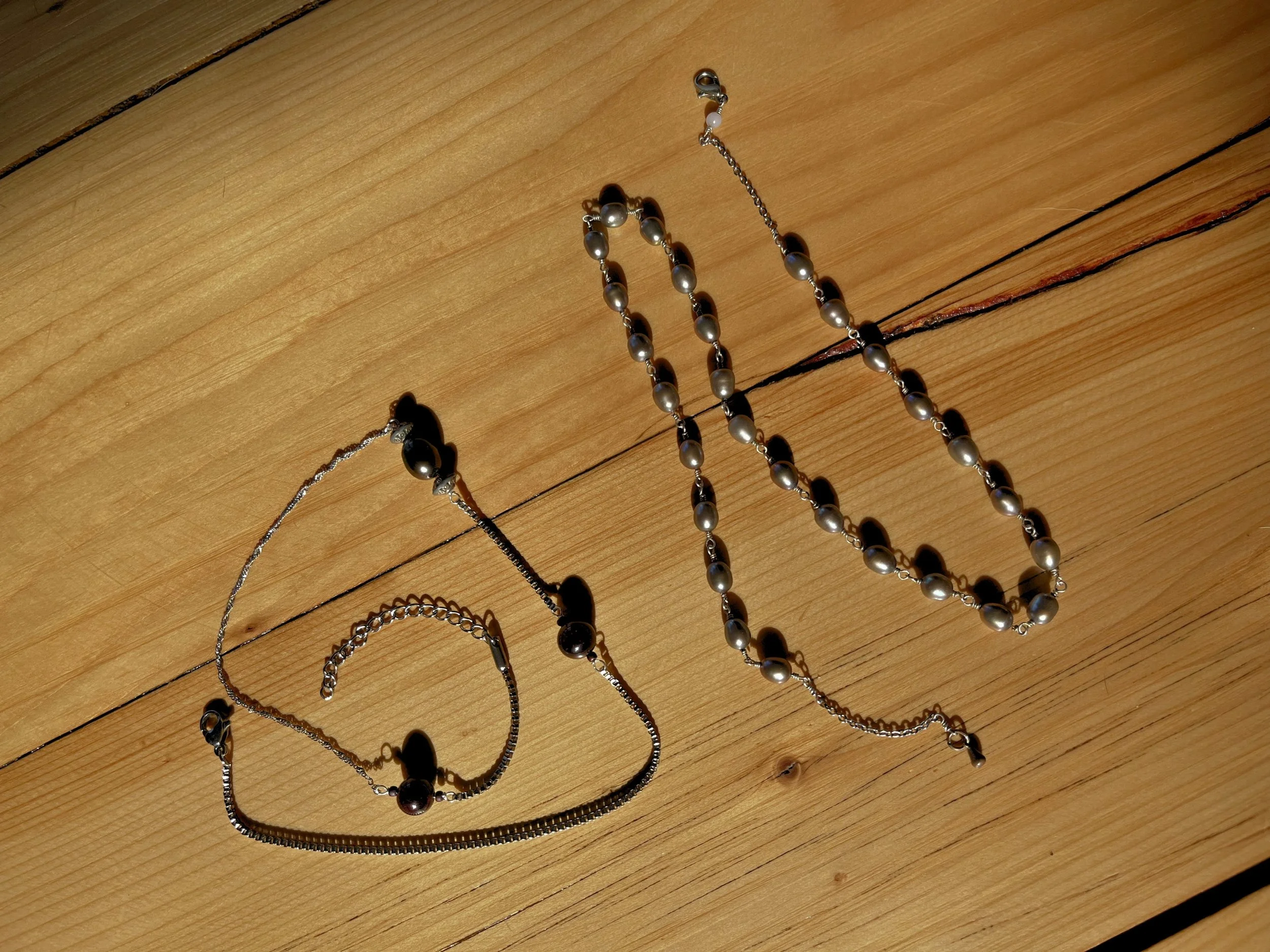 Set of pearl jewelry, including a necklace and a bracelet, placed on a wooden surface.