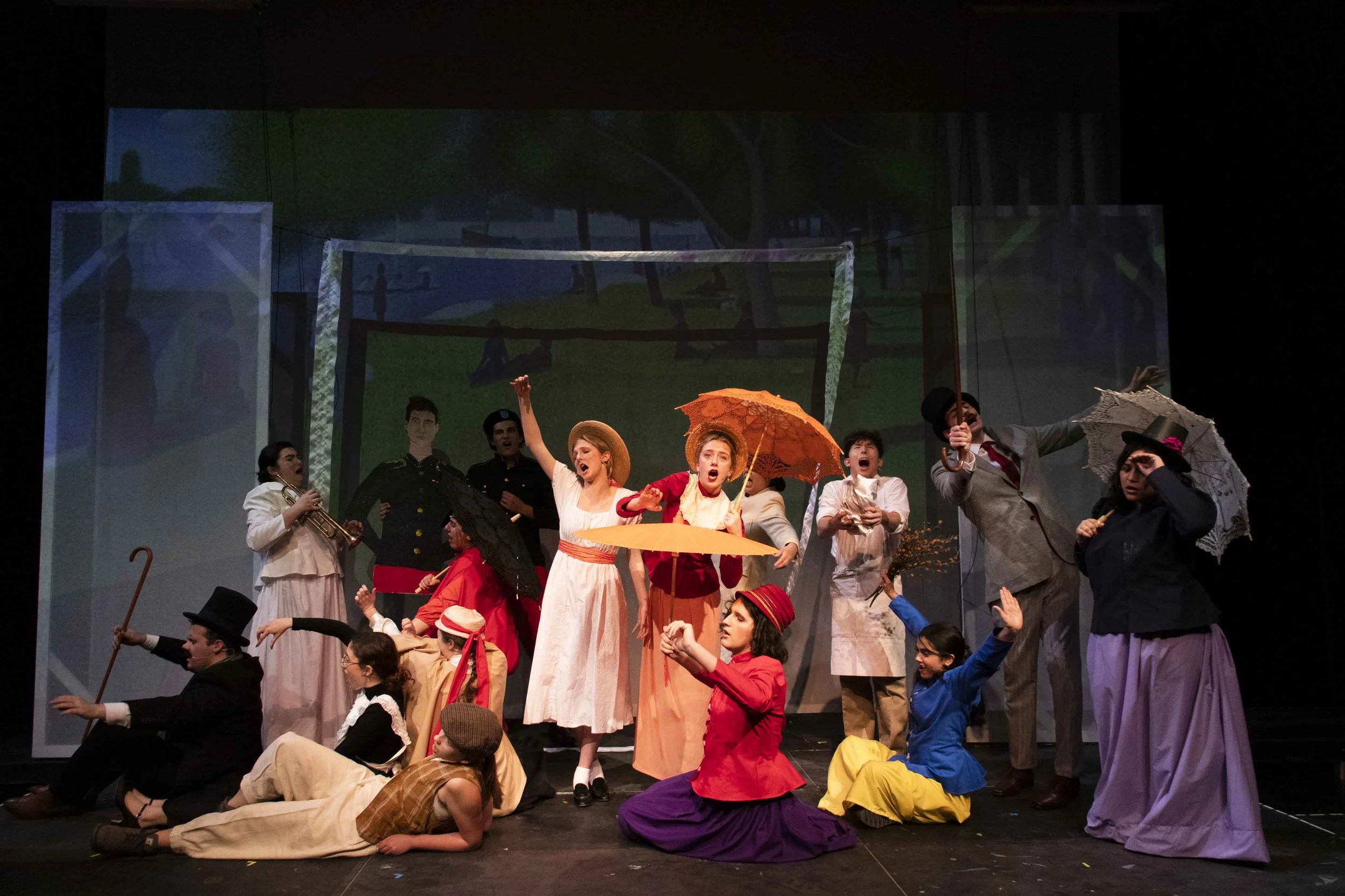 Scene from a stage play with actors dressed in 19th-century costumes, some holding umbrellas and props, performing a musical or theatrical scene.