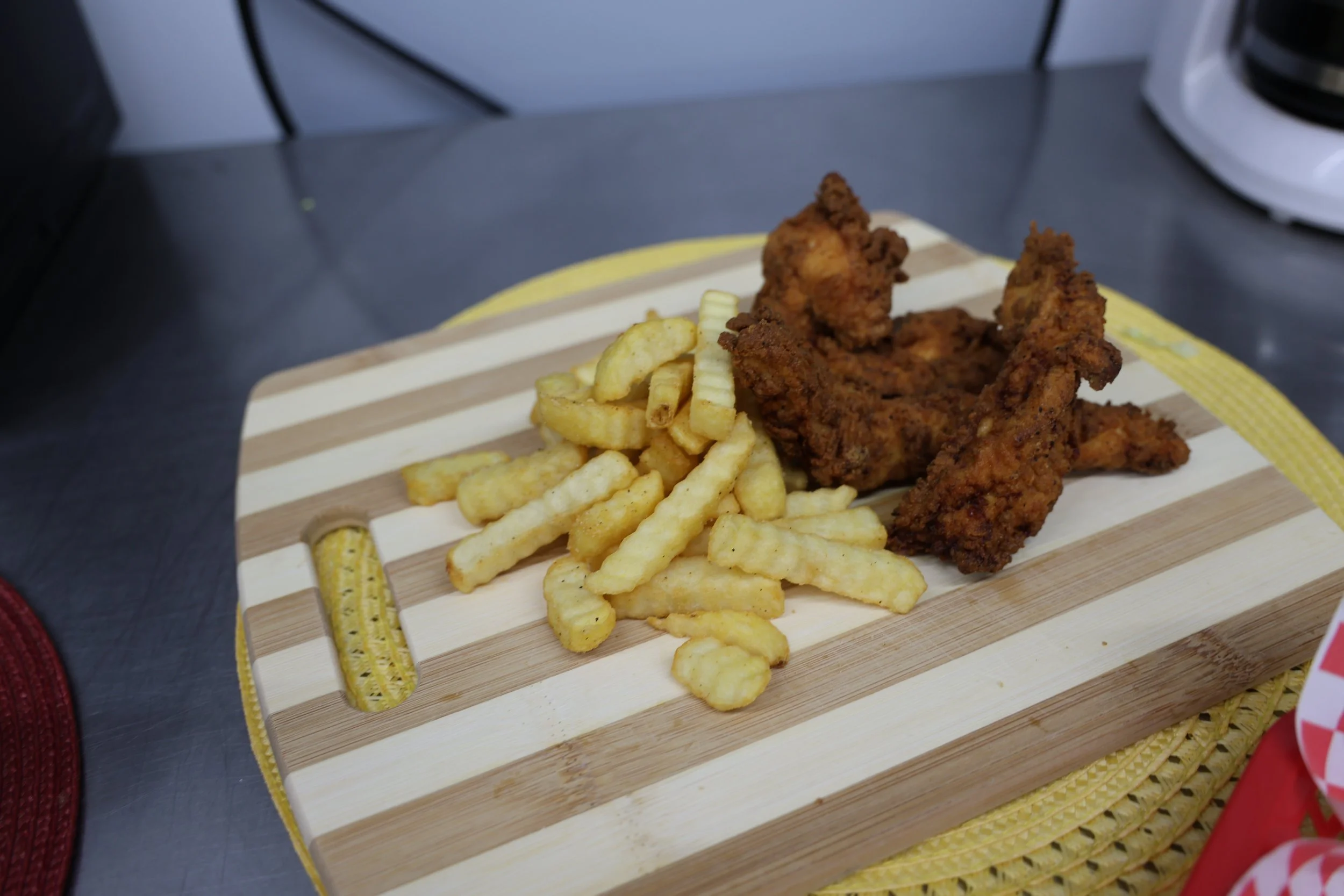 Crinkle-cut French fries and fried chicken pieces on a wooden serving board.
