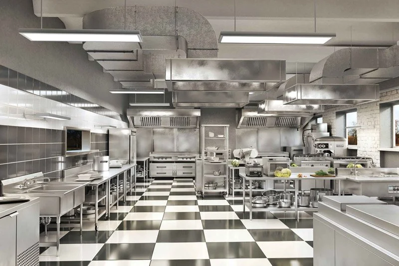 Commercial kitchen with stainless steel appliances, checkered black and white floor, and ventilation hoods.
