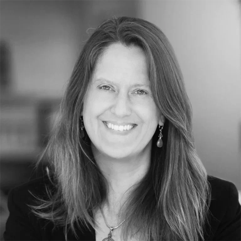 Black-and-white portrait of a woman with long hair smiling at the camera.