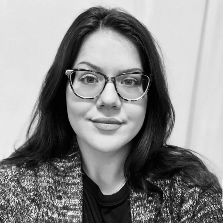A woman with dark hair and glasses smiling at the camera