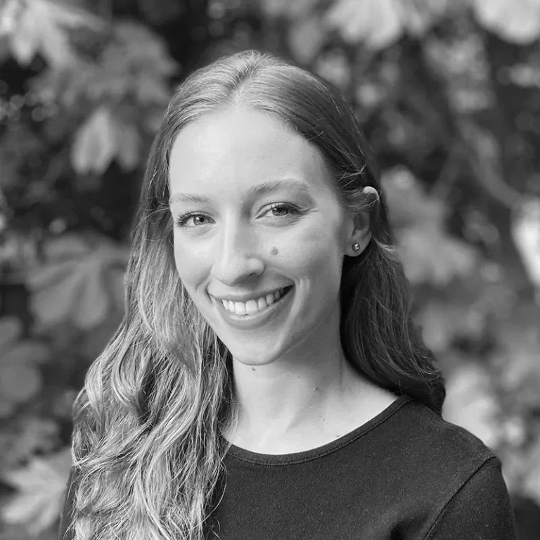 A woman with long wavy hair smiling outdoors, black and white photo.