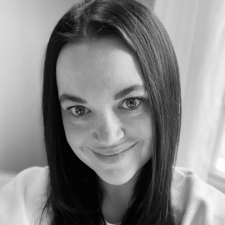 Black and white close-up photo of a woman with straight dark hair, smiling, in an indoor setting