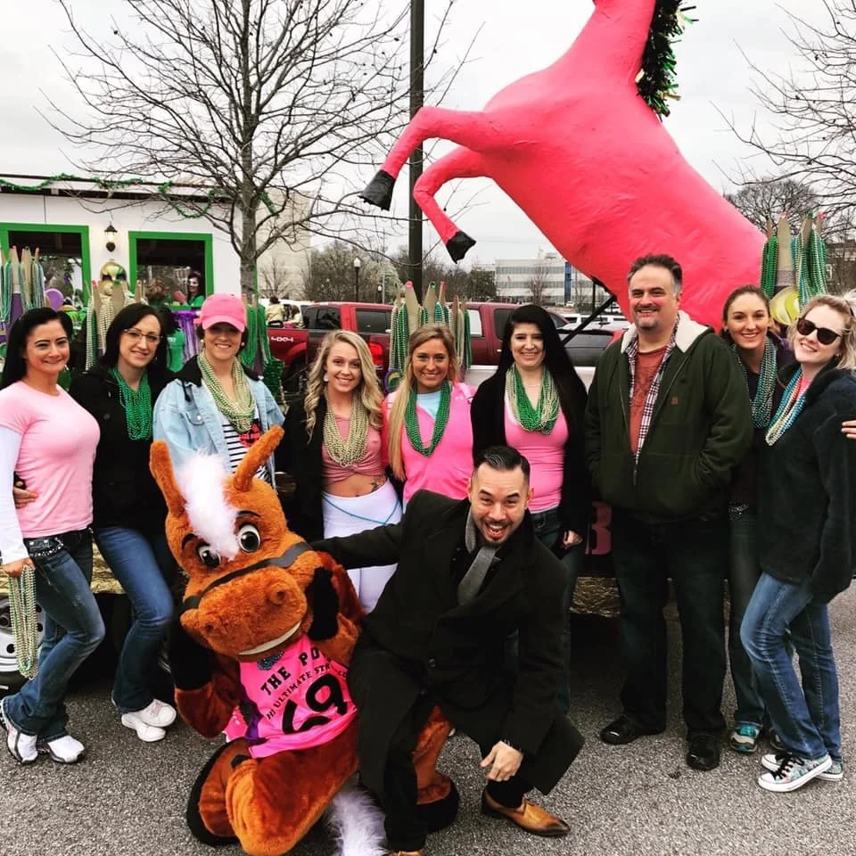 Jerry Westlund Presents team members participating in a Huntsville community parade with a decorated mascot, showcasing event promotion and local community engagement.