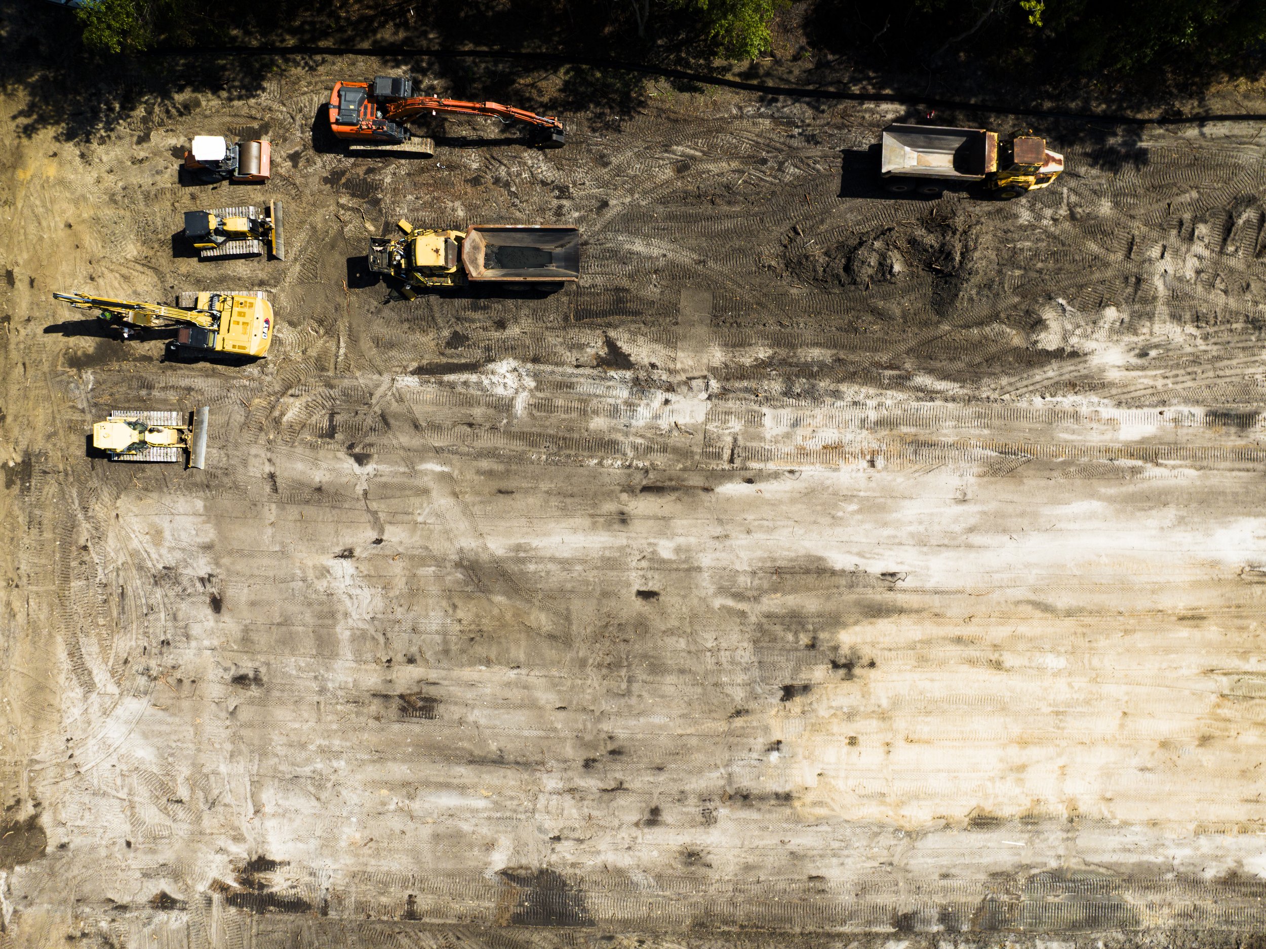 aerial view of construction site with multiple construction vehicles and dirt tracks.