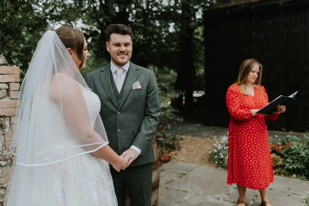 A bride and groom exchanging vows outdoors with Emily Ayres, South Wales celebrant officiating the wedding ceremony.