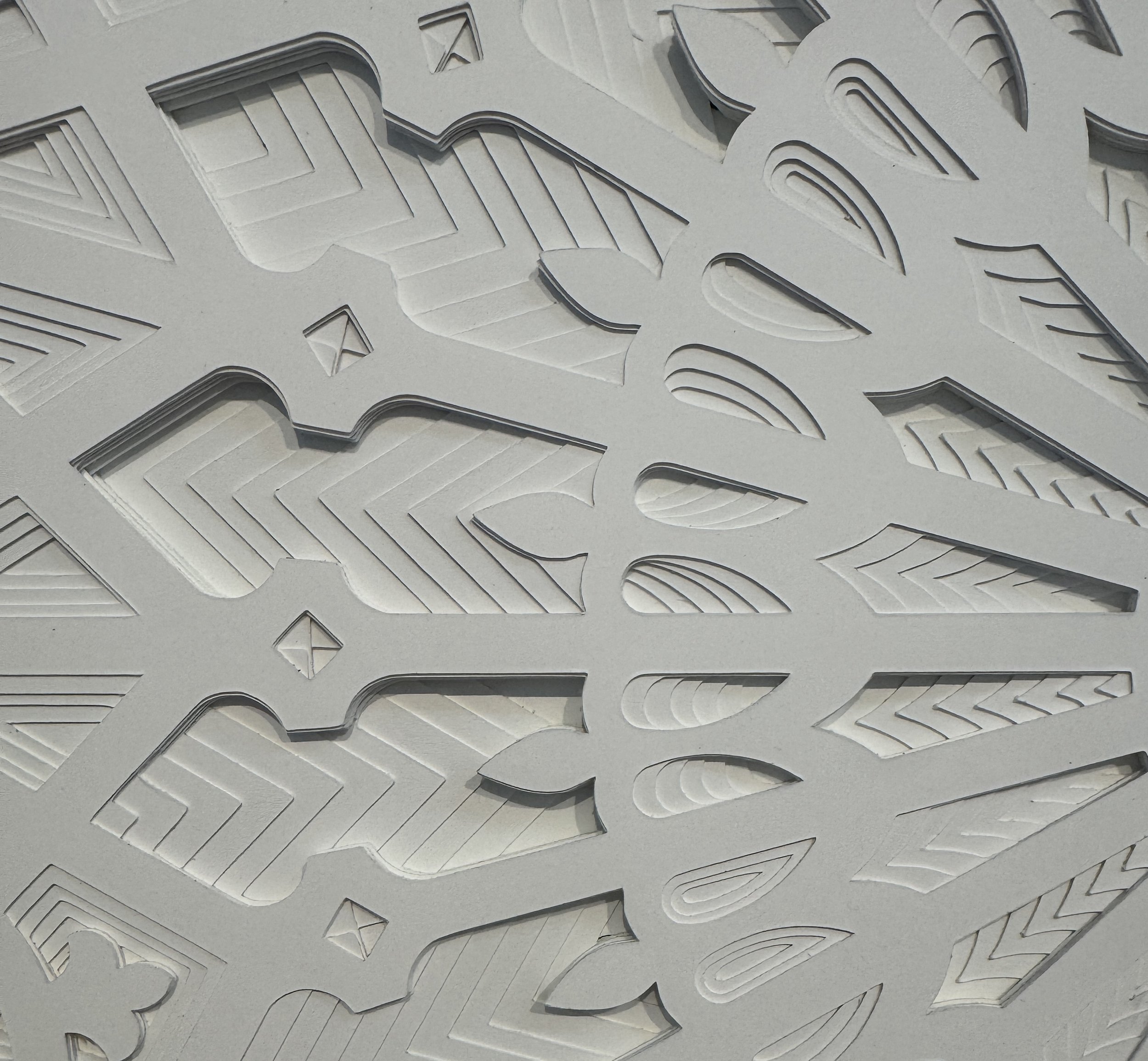 Close-up of layered white paper with intricate cut-out patterns resembling a geometric or floral design.
