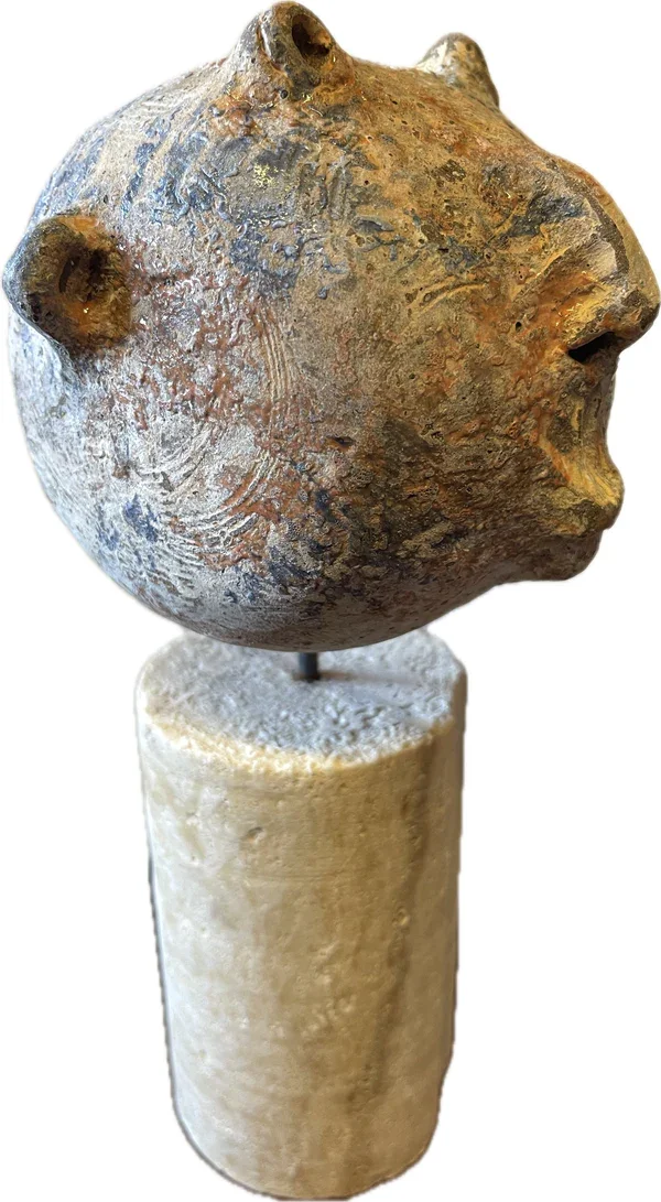 one of a kind ceramic head on a stone pedestal.webp