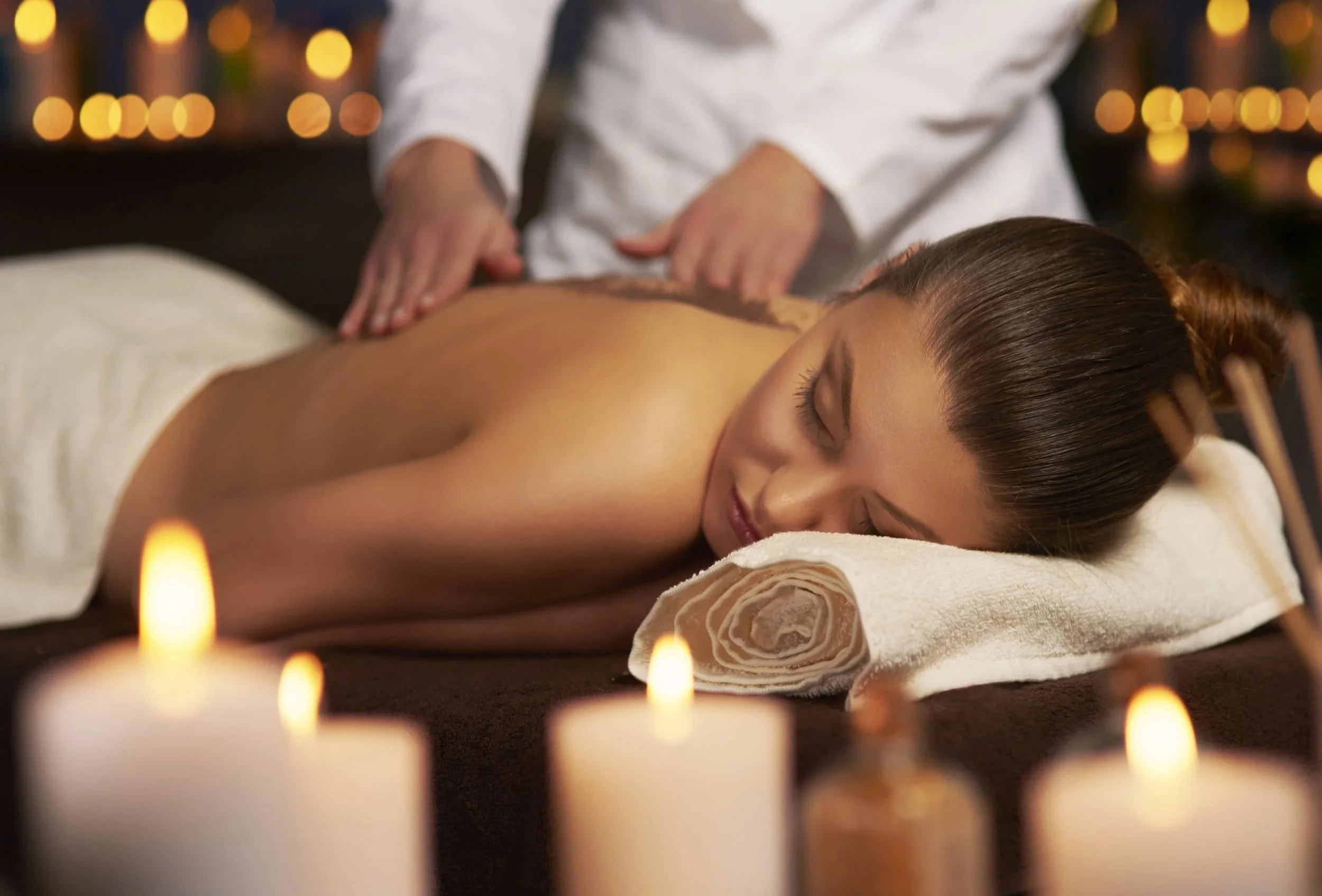 Woman receiving a massage in a dimly lit room with candles.
