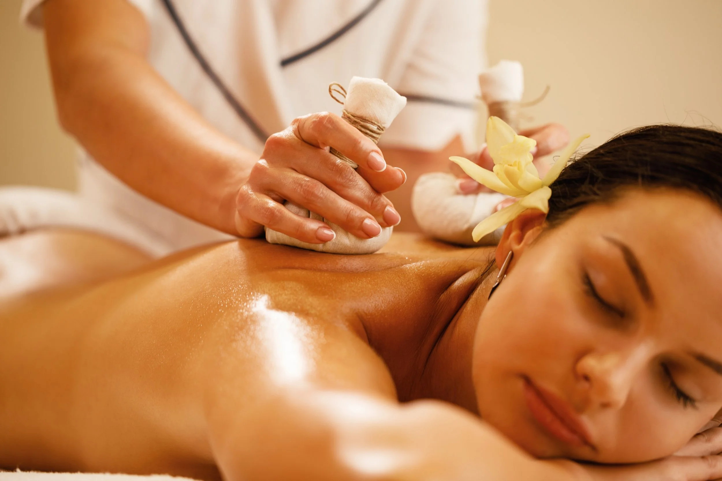 A woman receiving a massage with a flower placed behind her ear