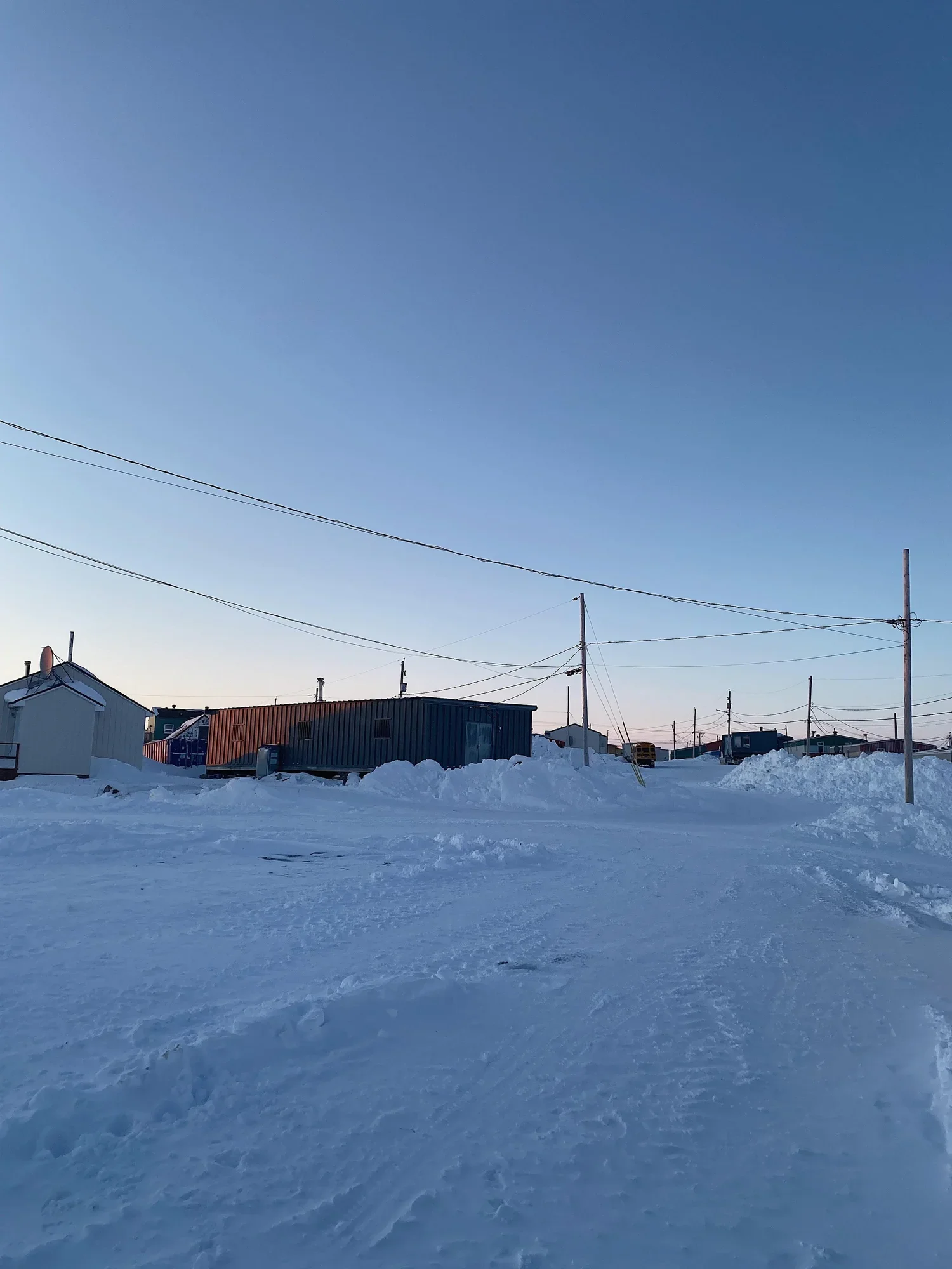 Vue d'un paysage enneigé avec des maisons en métal colorées sous un ciel clair et dégagé.
