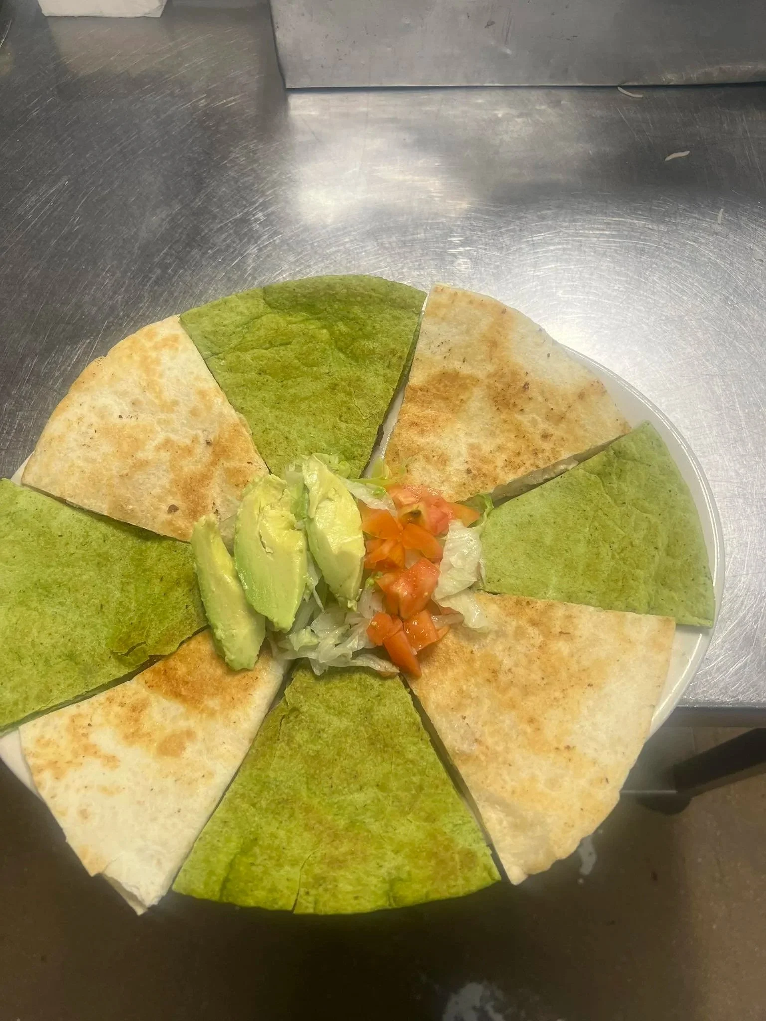 Plate of six quesadillas with sliced avocado and tomato garnish in center