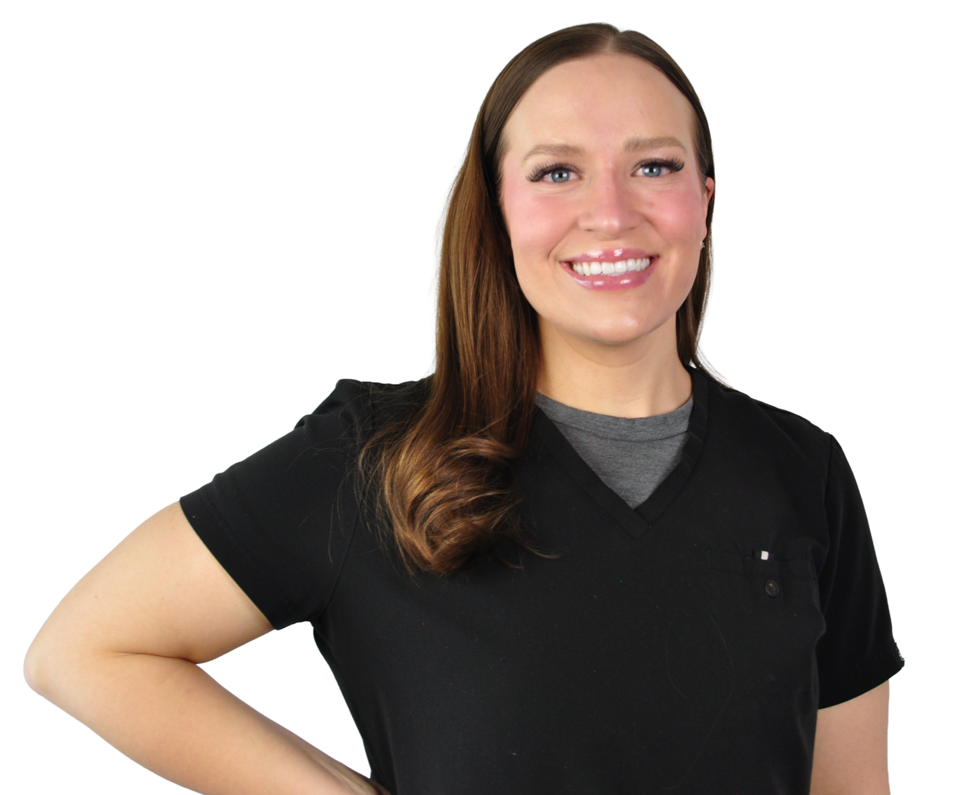 A woman with long brown hair, blue eyes, and a bright smile, wearing black scrubs with a gray shirt underneath, standing with her hand on her hip.