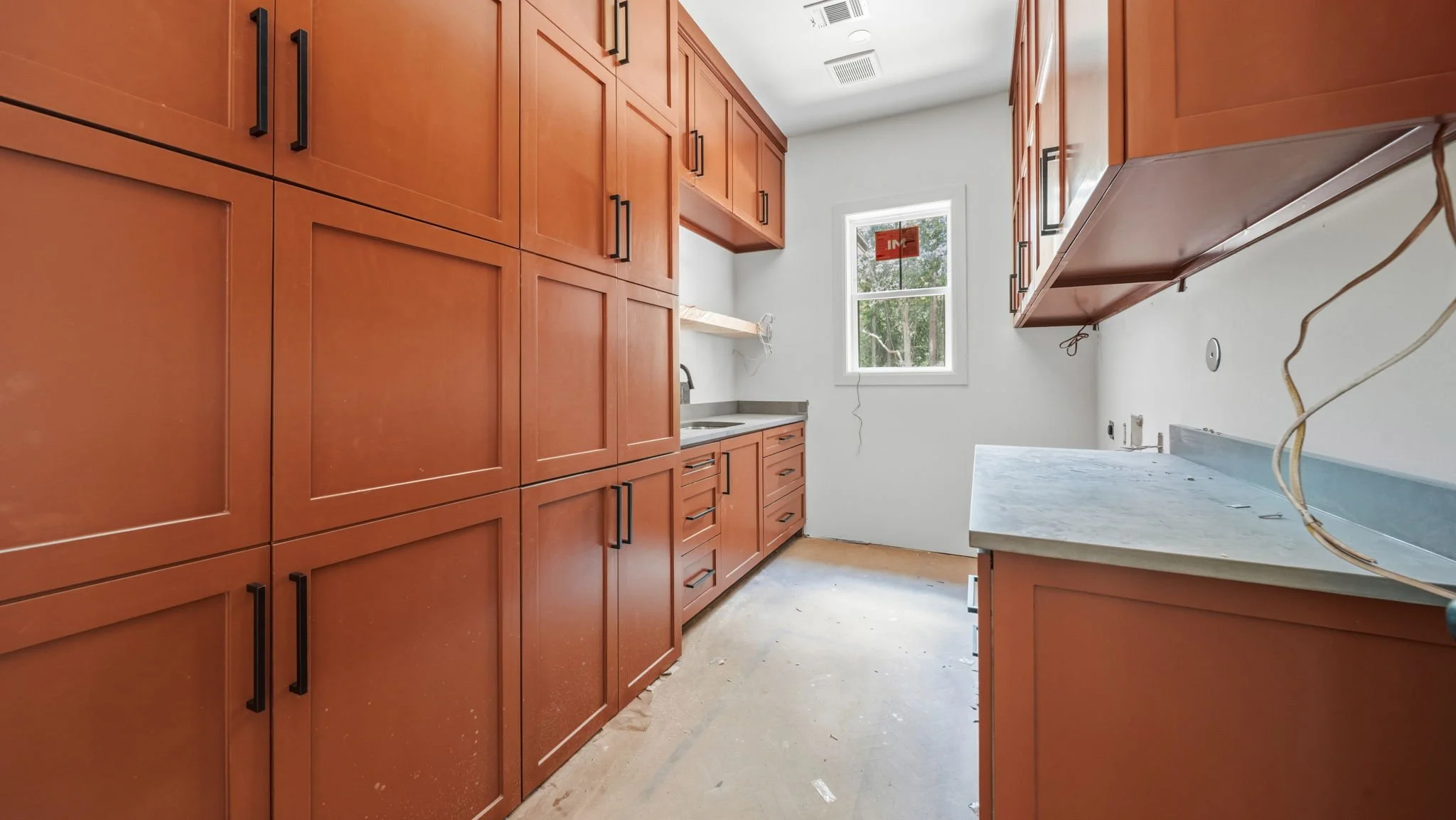 Kitchen under construction with wooden cabinets, a small window, and some exposed wires.