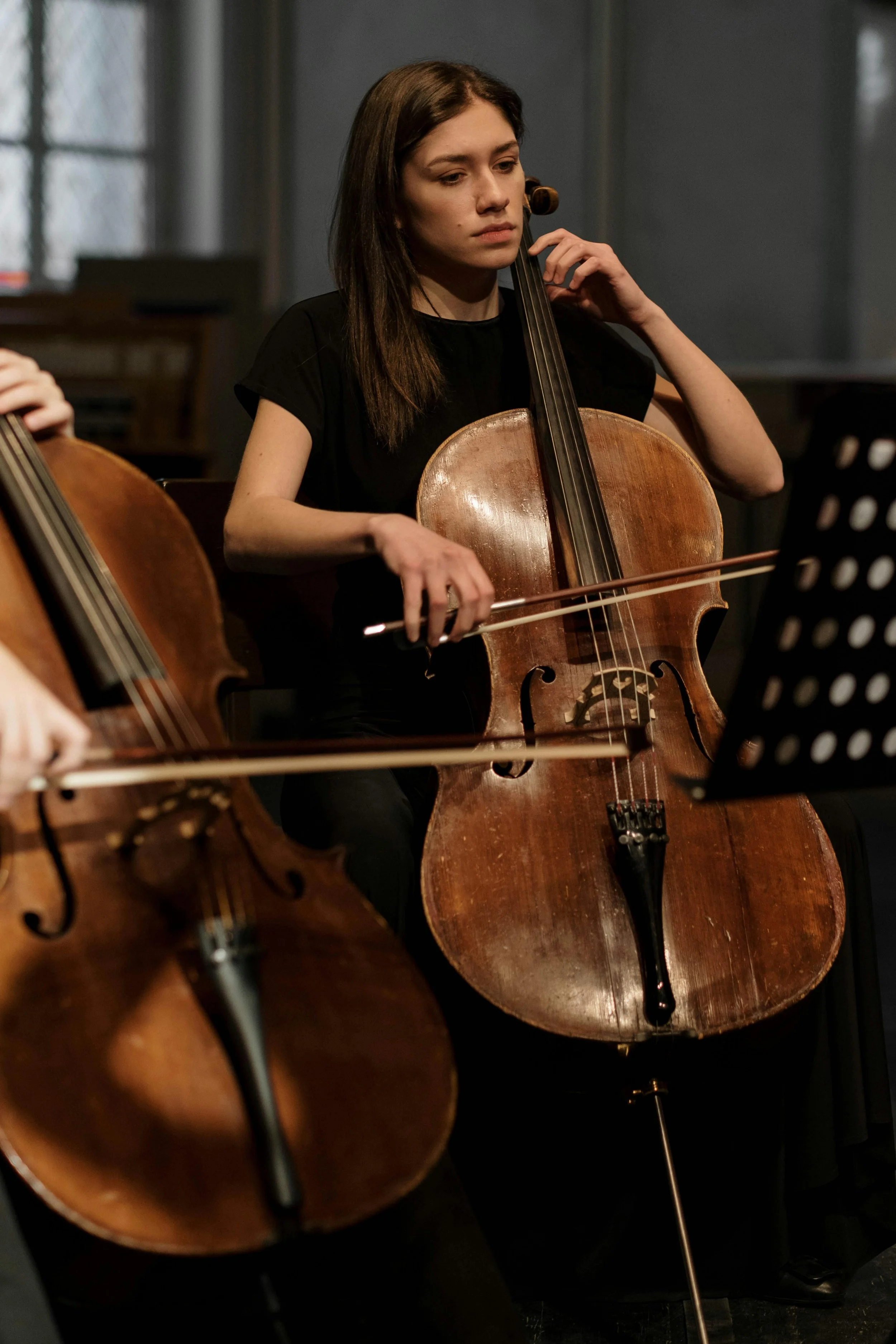 Young woman playing a cello during an orchestra rehearsal.