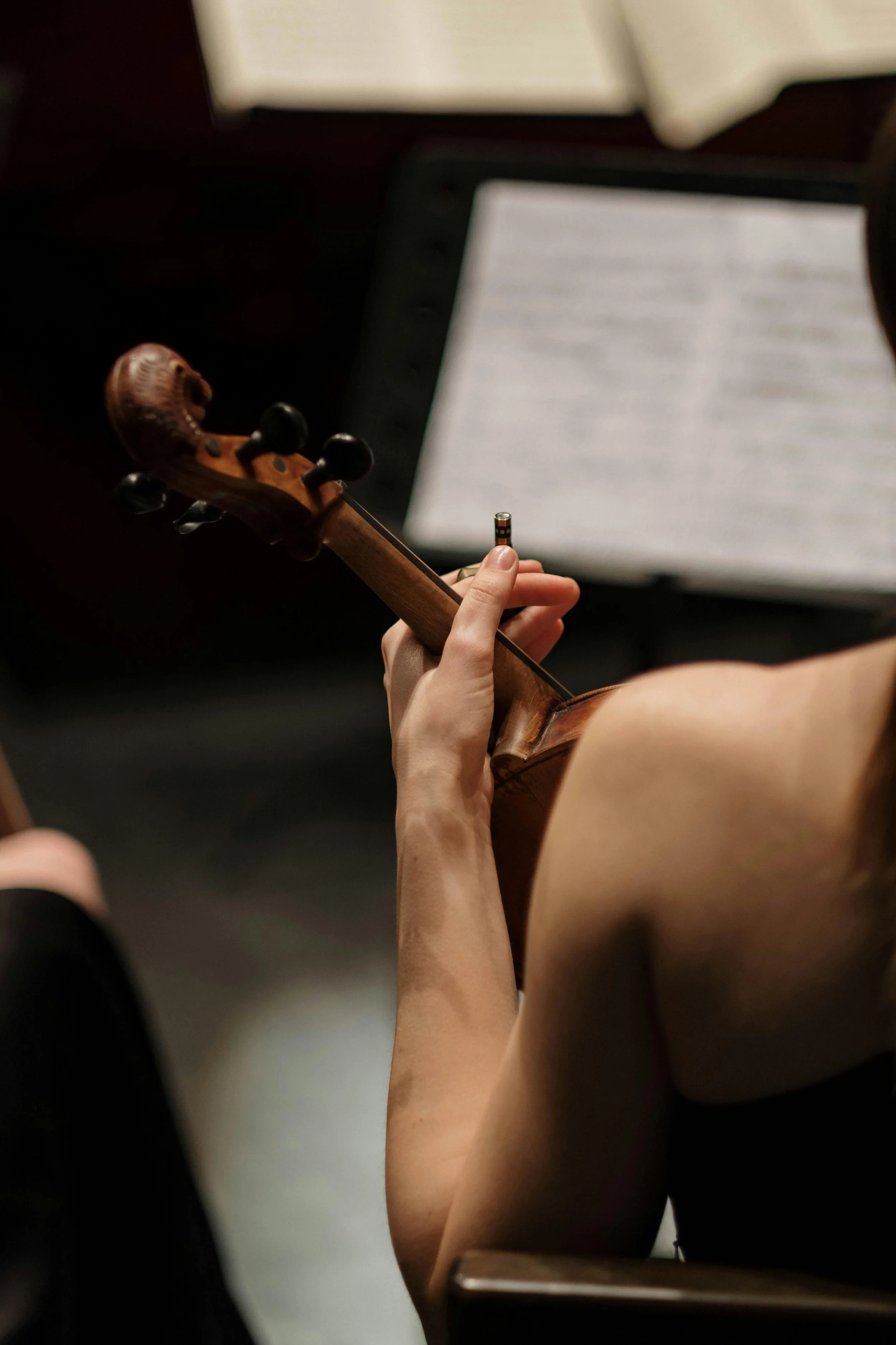 A person playing a violin with sheet music on a music stand in the background.