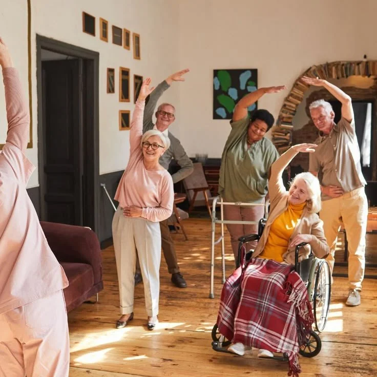 Older adults dancing and exercising together in a room with wooden floors and modern wall art.