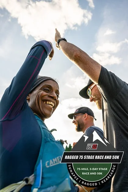 Celebrating runners at the finish line of a race, with a woman smiling and high-fiving a man, on a partly cloudy day during the Ragged 75 Stage Race and 50K.
