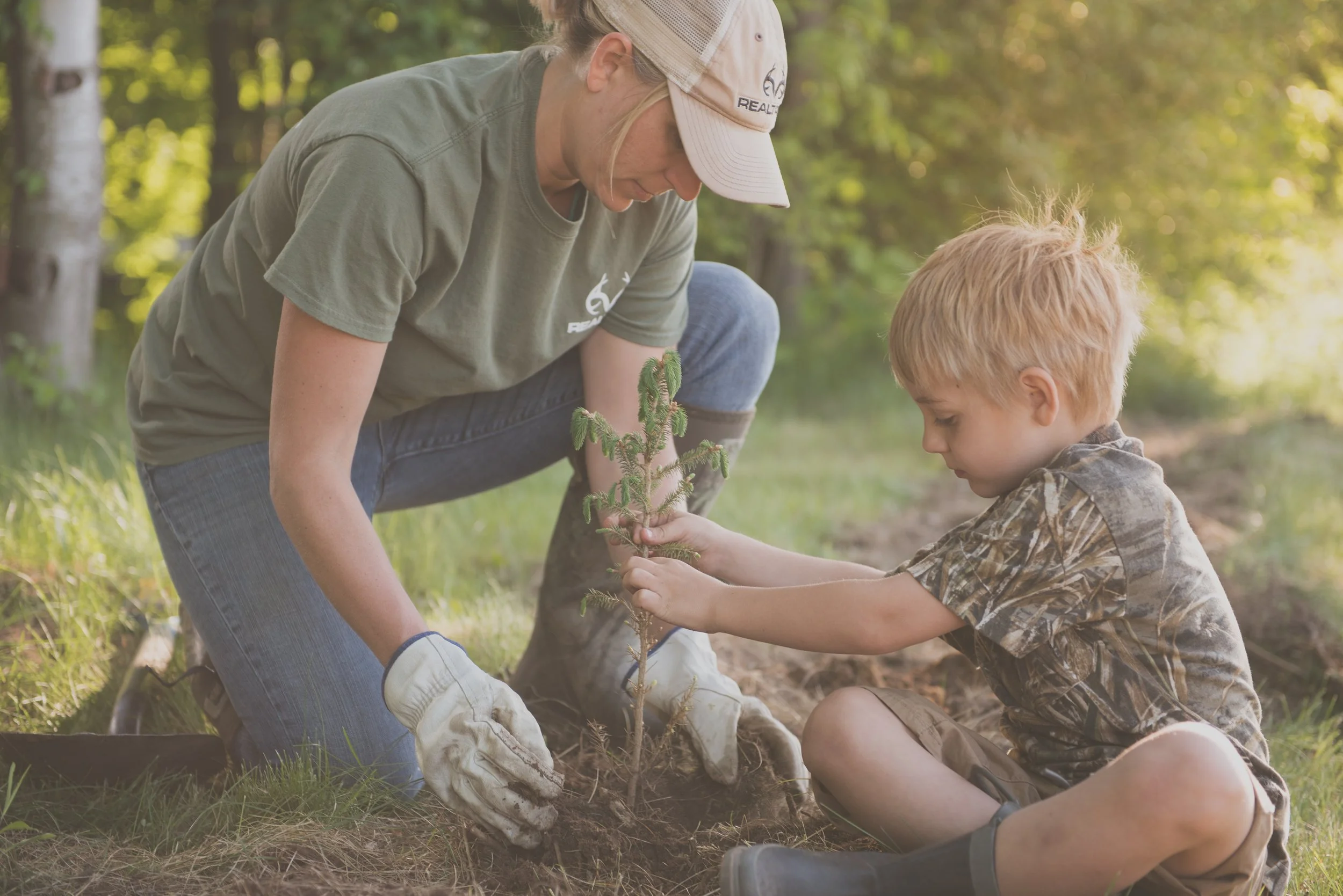 Woman and child wearing Realtree apparel planting a sprout