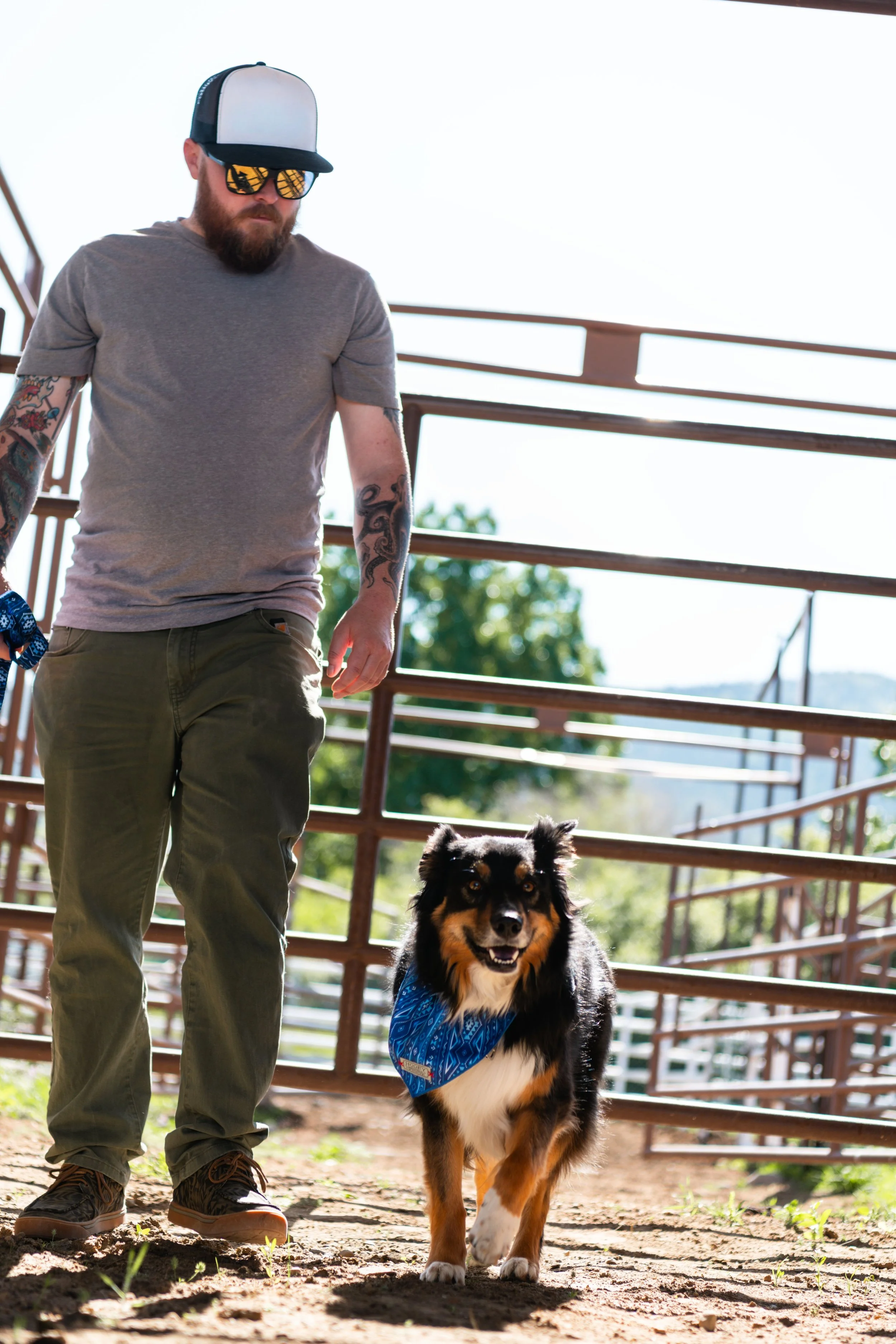 Man with a dog wearing Hooey dog bandana on a barn