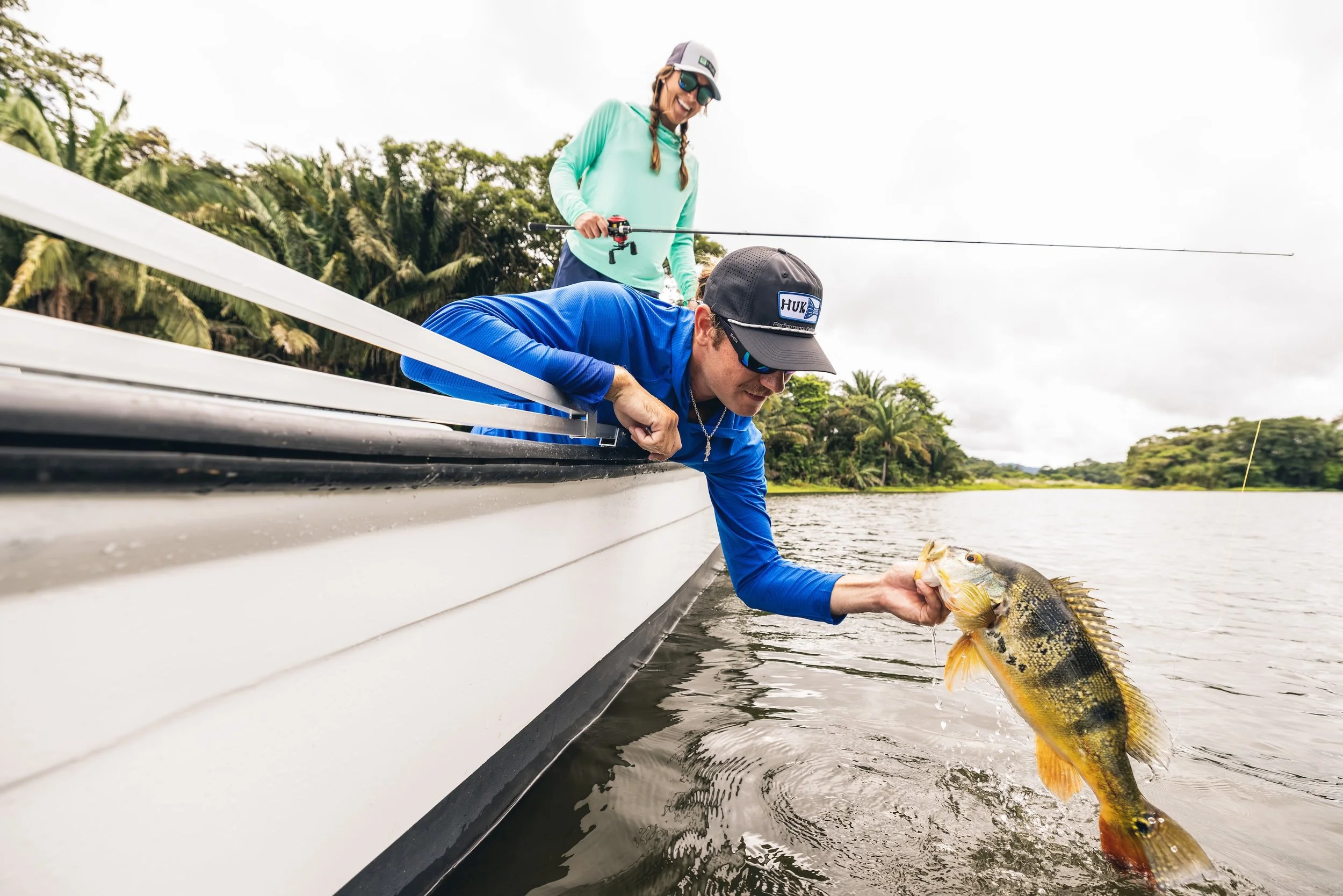 Two people wearing Huk apparel on a fishing boat