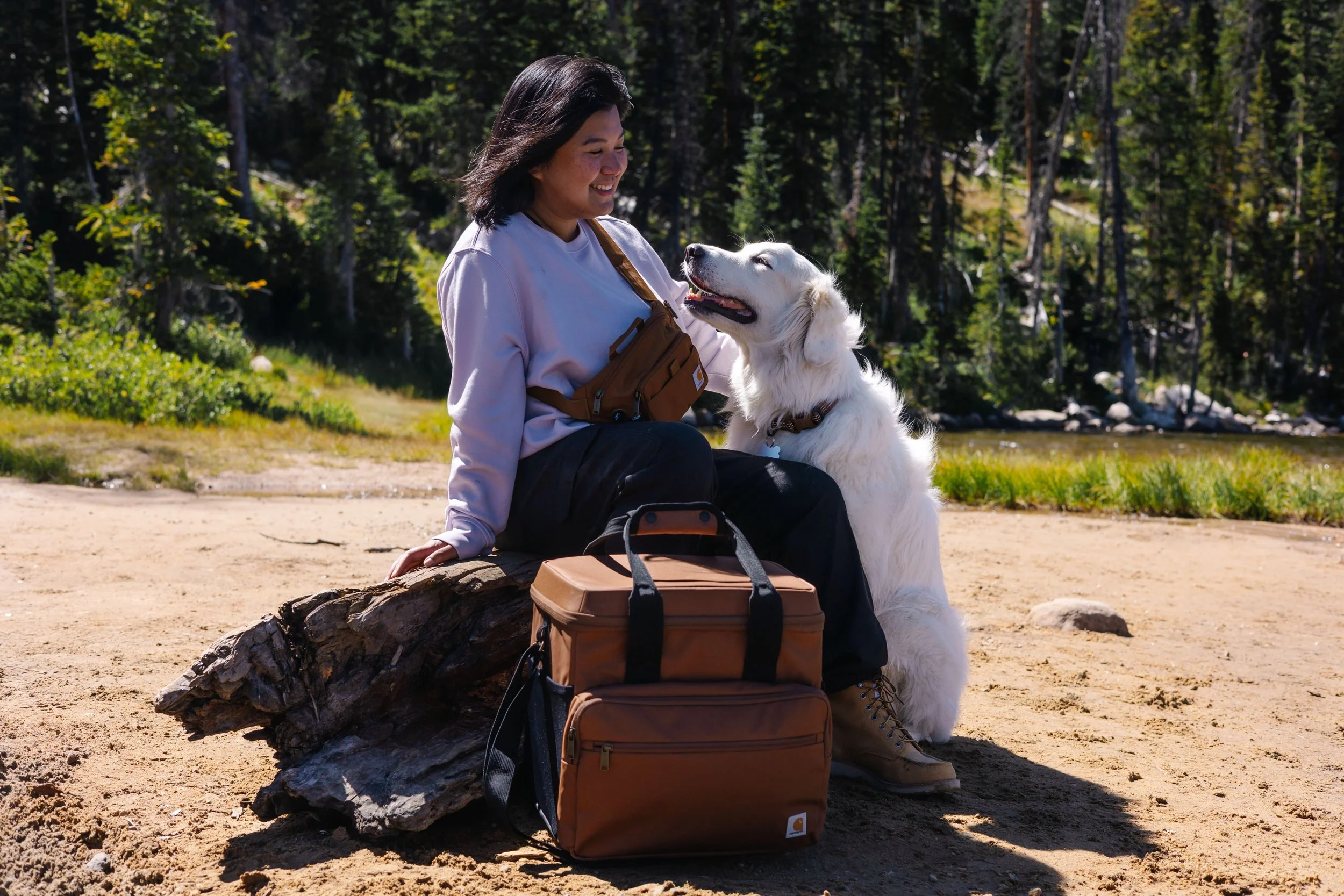 Woman and her dog outside by the lake with Carhartt bags