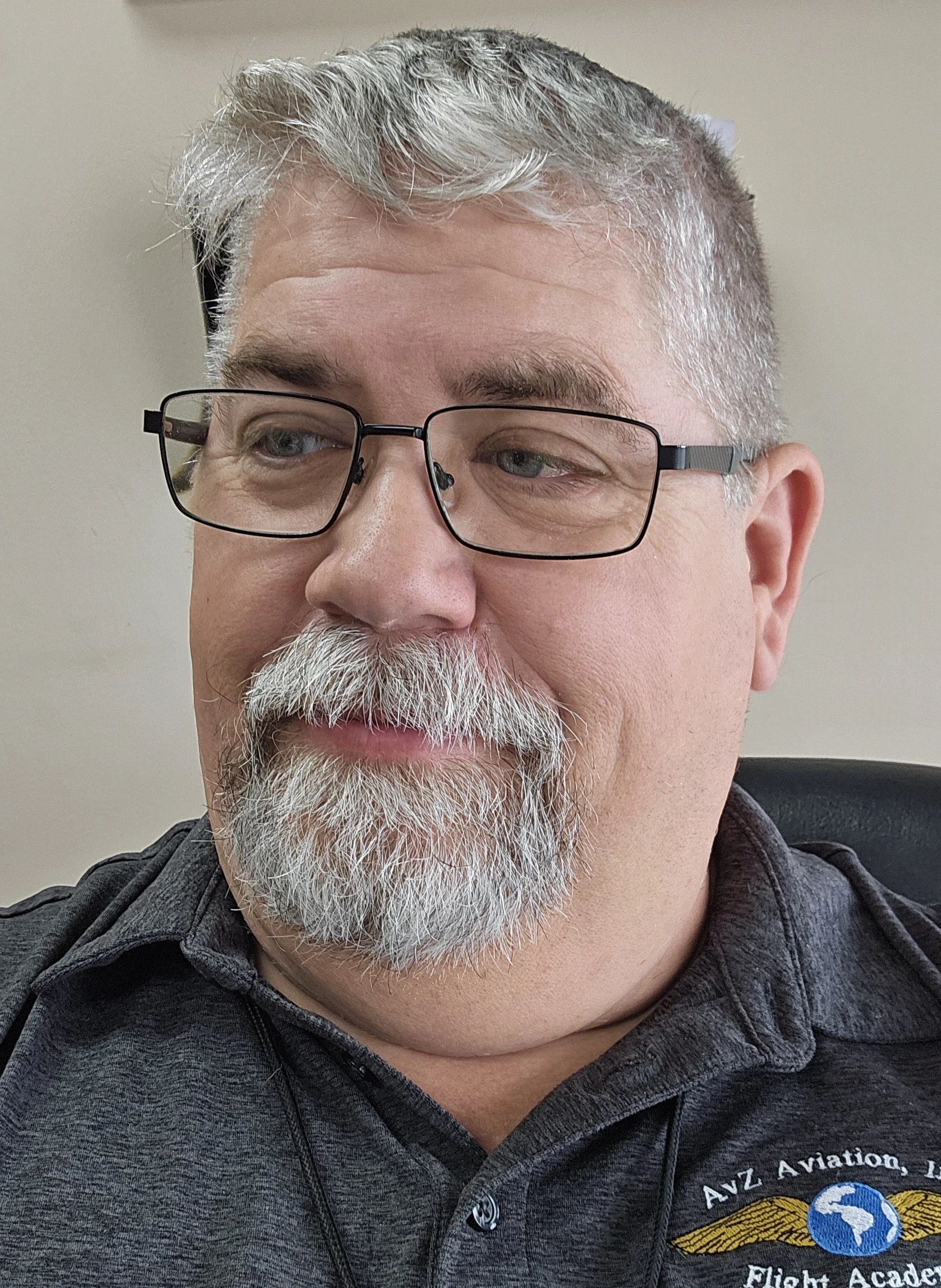 A headshot of our chief flight instructor, Stephen Abrew. In this photo, Stephen is wearing a gray shirt with our school's old logo, and is looking slightly to the left.