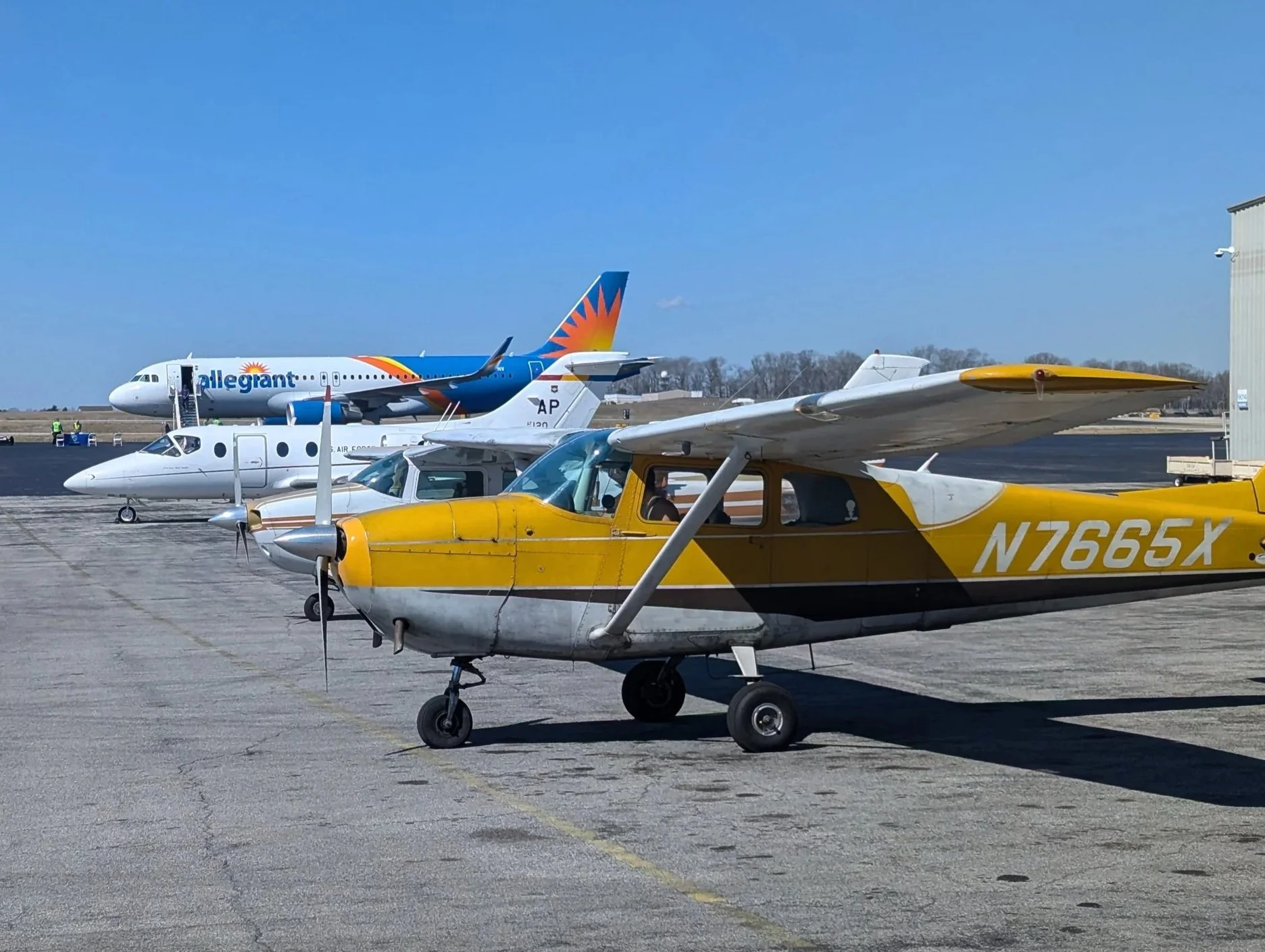 A series of planes parked behind AvZ Flight Academy. From front to back: a Cessna Skyhawk (owned by AvZ), a Cessna Centurion, A Raytheon T-1A, and an Airbus A320.