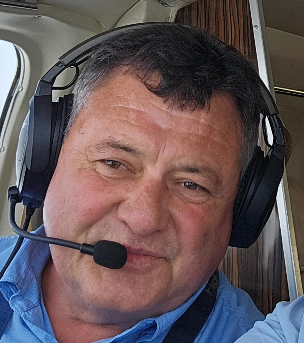 Adrian Van Zyl, the school's owner, wearing a headset with a microphone, smiling inside a plane.