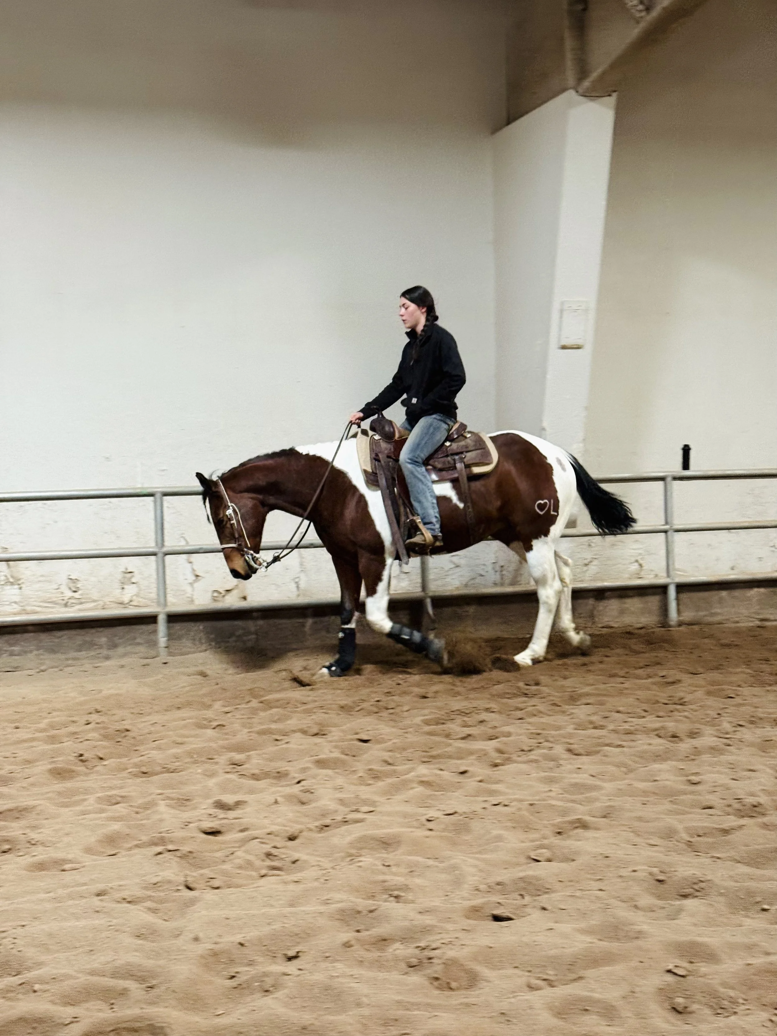 Woman riding a horse in an indoor arena.