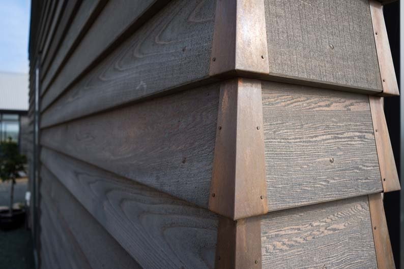 Close-up of a wooden exterior wall with horizontal planks and corner trim, outdoors.