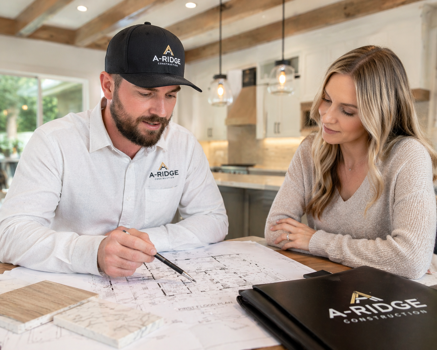 A-Ridge Construction design-build consultation with homeowner reviewing remodeling floor plans, material samples, and project details in a custom kitchen renovation.