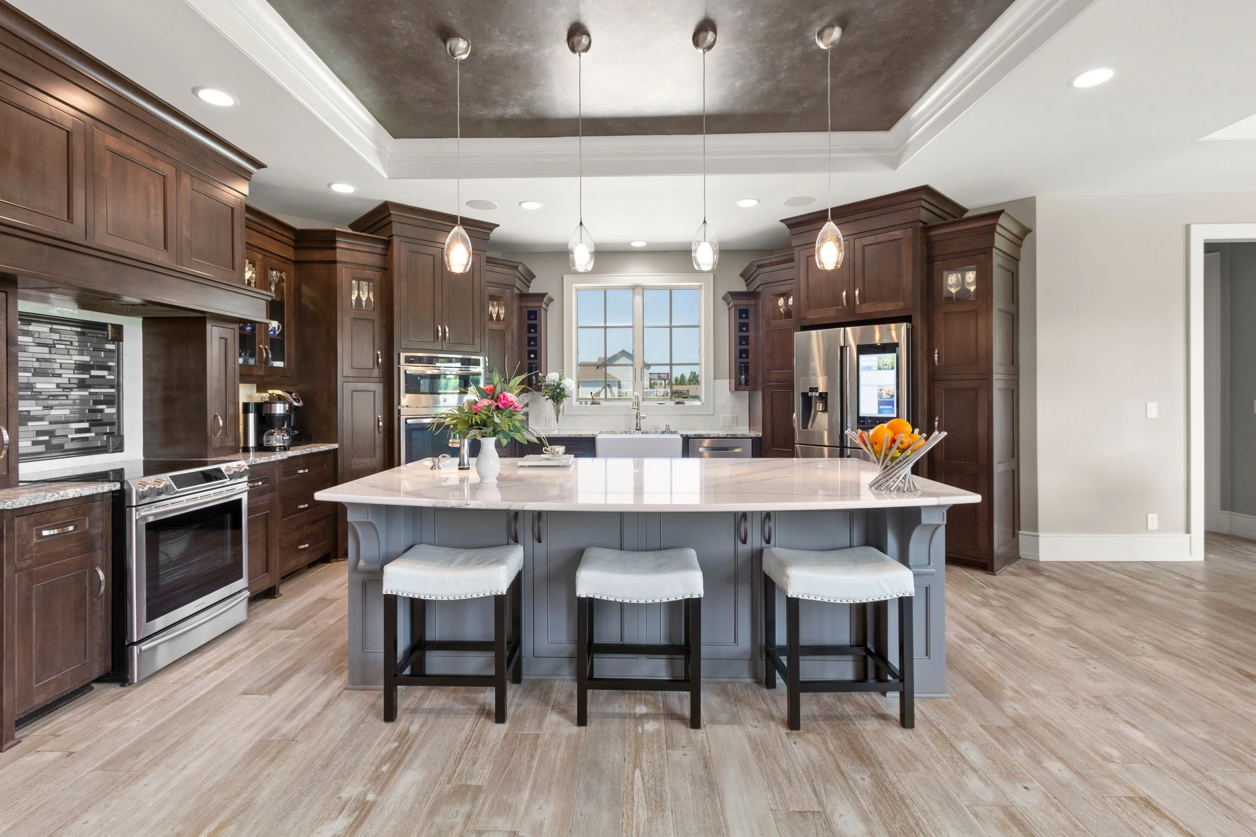 Luxury kitchen remodel with dark custom cabinets, large quartz island, pendant lighting, and open layout by A-Ridge Construction.