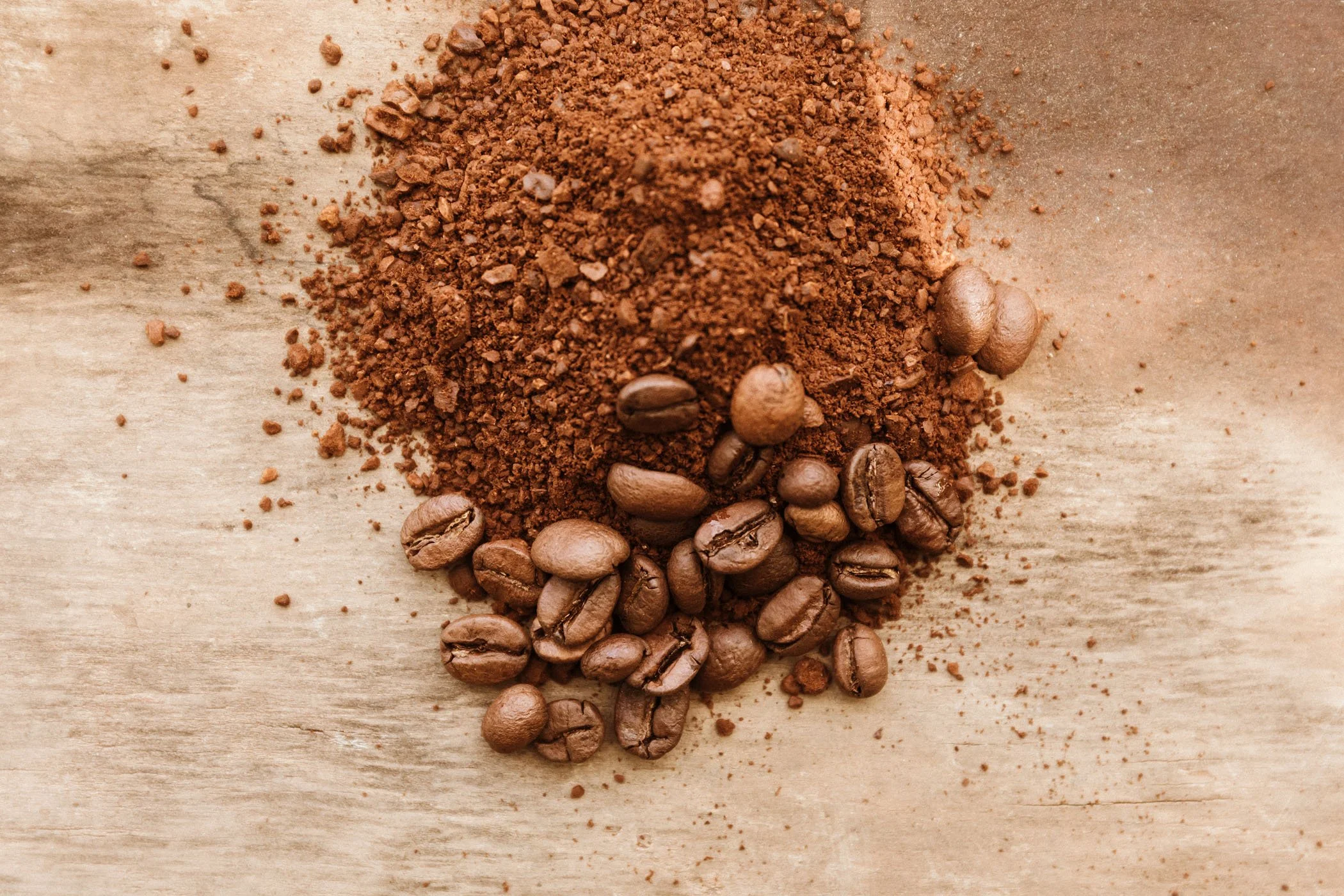 Café molido y granos de café sobre una superficie de madera.