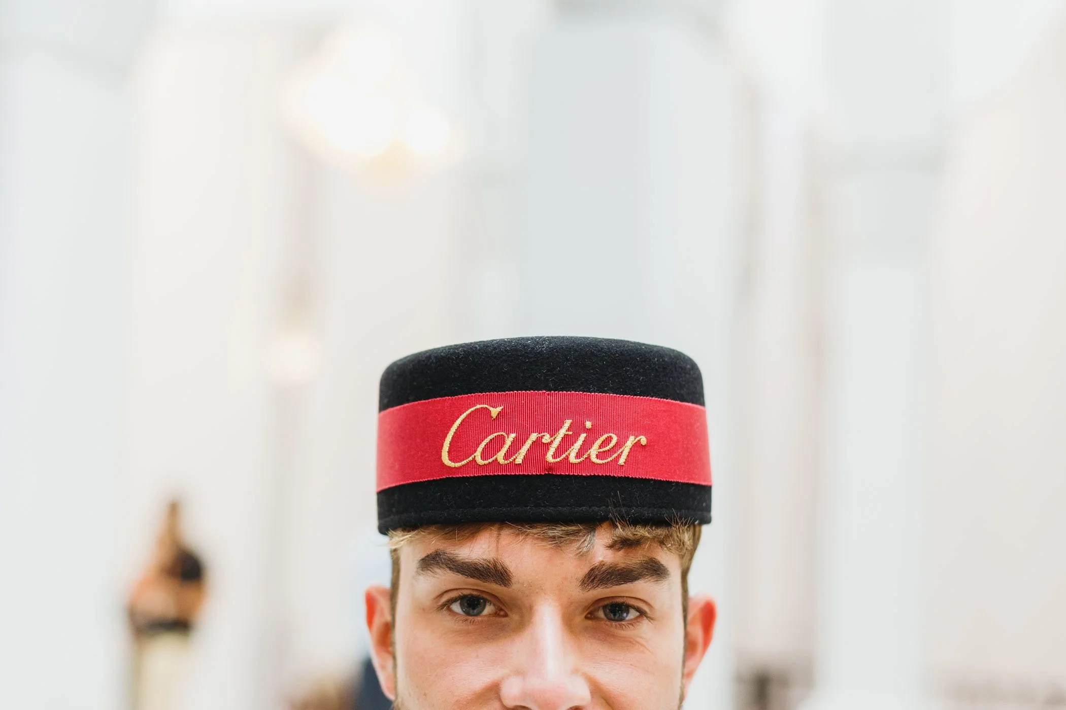 Joven con sombrero estilo cartujo con la palabra 'Cartier' en rojo